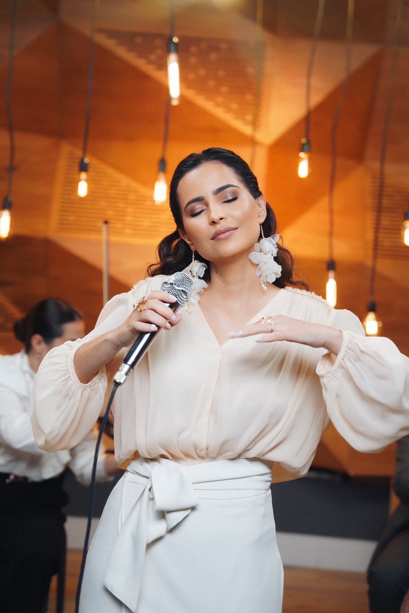 A Renata interpretando uma musica com braços abertos e olhos fechados